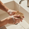 Hands lathering a Bera Botanicals natural soap bar at the sink