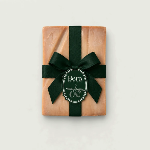 Bera Botanicals gift card shown as an Aleppo soap bar wrapped in dark green ribbon.